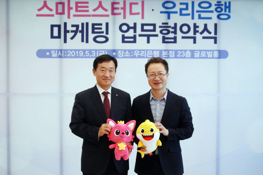 정채봉(사진 왼쪽) 우리은행 영업부문장과 이승규 스마트스터디 CFO 가 핑크퐁과 아기상어 인형을 들고 기념사진 촬영을 하고 있다.(사진=우리은행)